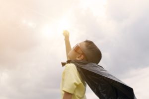 a kid dressed as superhero looking up the sky