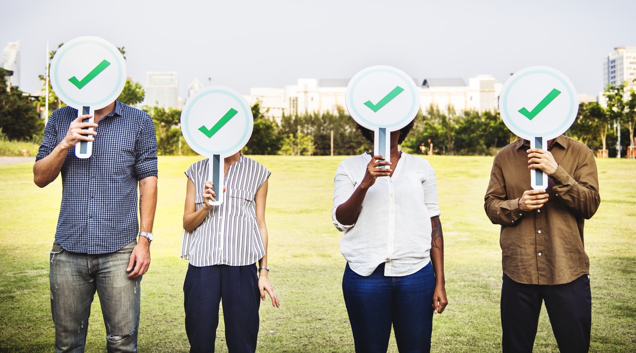 four people in the yard with green checklist sign
